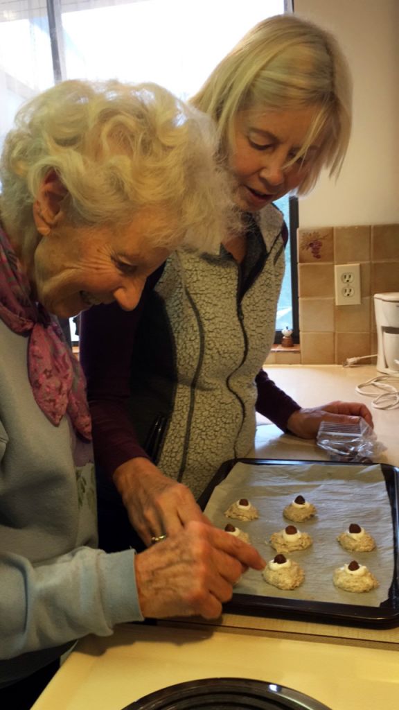 Two women in the kitchen placing hazelnut macaroons on a baking sheet