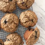Six blueberry bran spelt muffins cooling on a wire rack, one muffin turned on its side.