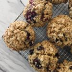 Raspberry oatmeal spelt muffins cooling on a metal rack on a white marbled countertop