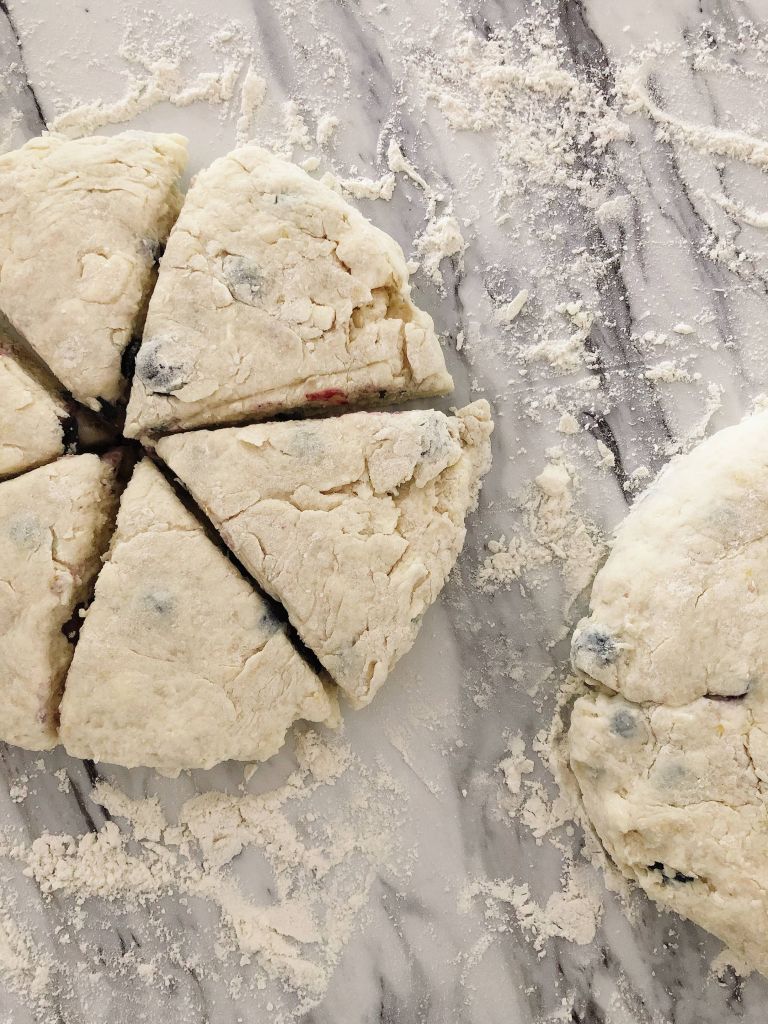 Lemon blueberry spelt scones dough shaped and sliced on a white countertop