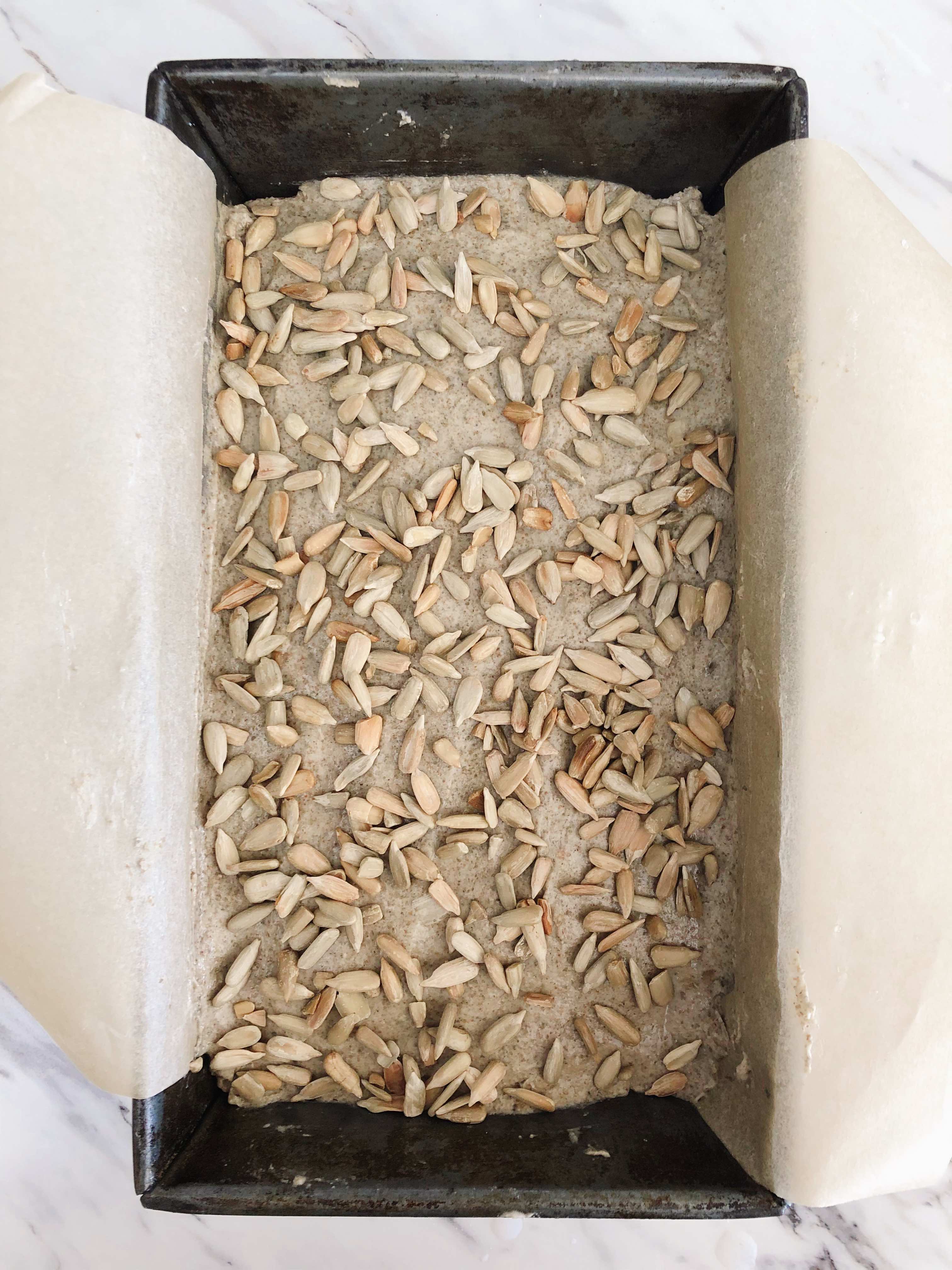 A loaf of whole grain rye sourdough bread with sunflower seeds on top before proofing