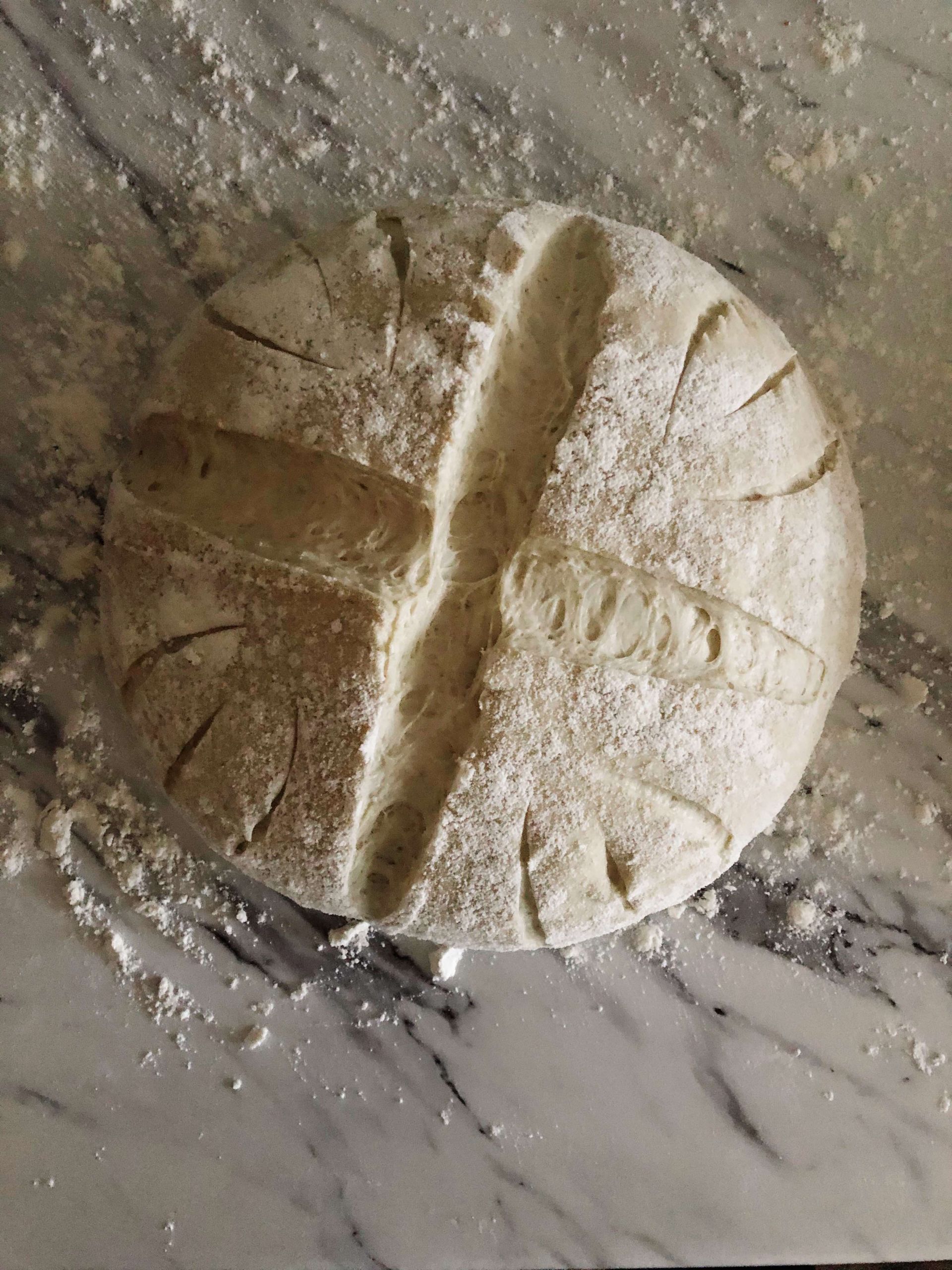 Spelt, einkorn and rye bread dough scored with an X and ready to be baked