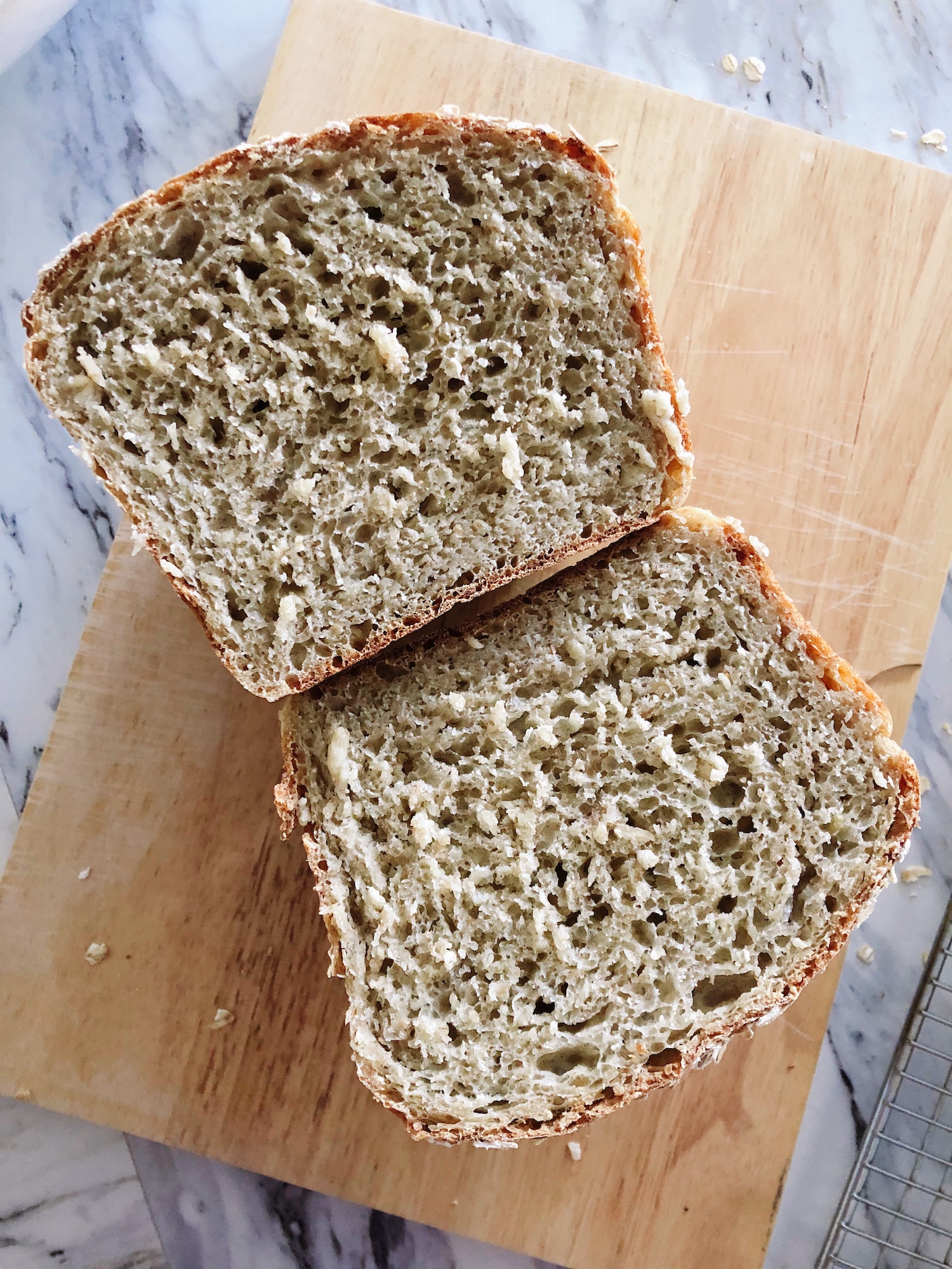 A loaf of oats, honey and spelt no knead bread cut in half and opened to reveal the inside of the loaf.